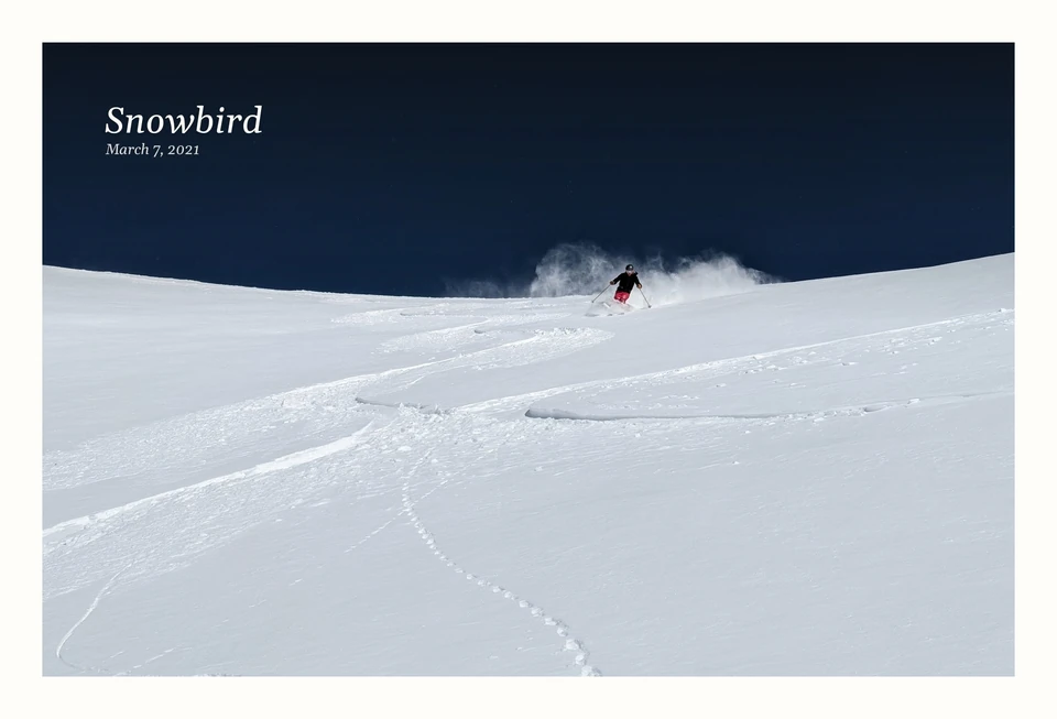 A photograph of a skier carving through fresh powder beneath a deep blue sky. Snowbird, March 7, 2021.